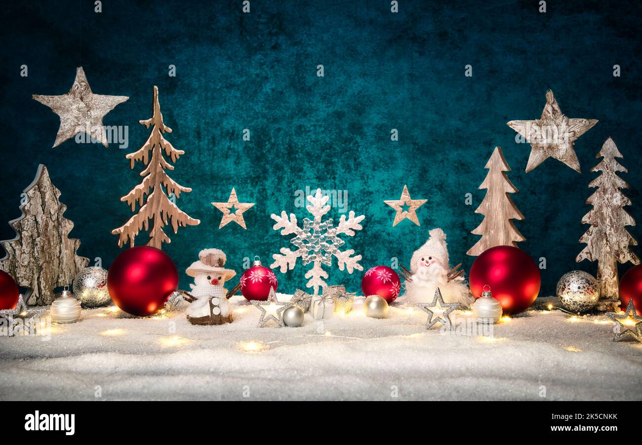 Christmas ornamental arrangement with stylish teal copy space, red and silver baubles, lights, snow, wooden decoration and snowman figures Stock Photo