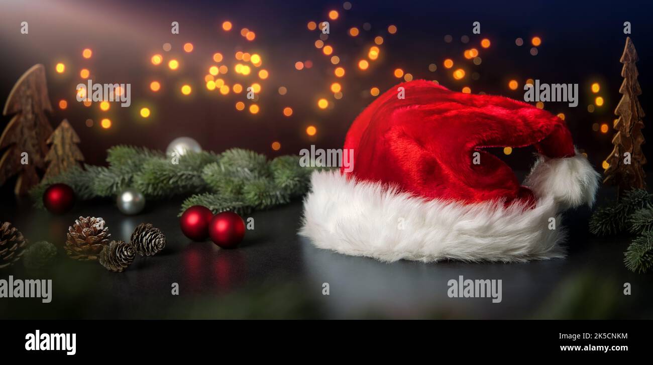 Christmas decoration arrangement with Santa's hat, ornaments and lights on dark background Stock Photo