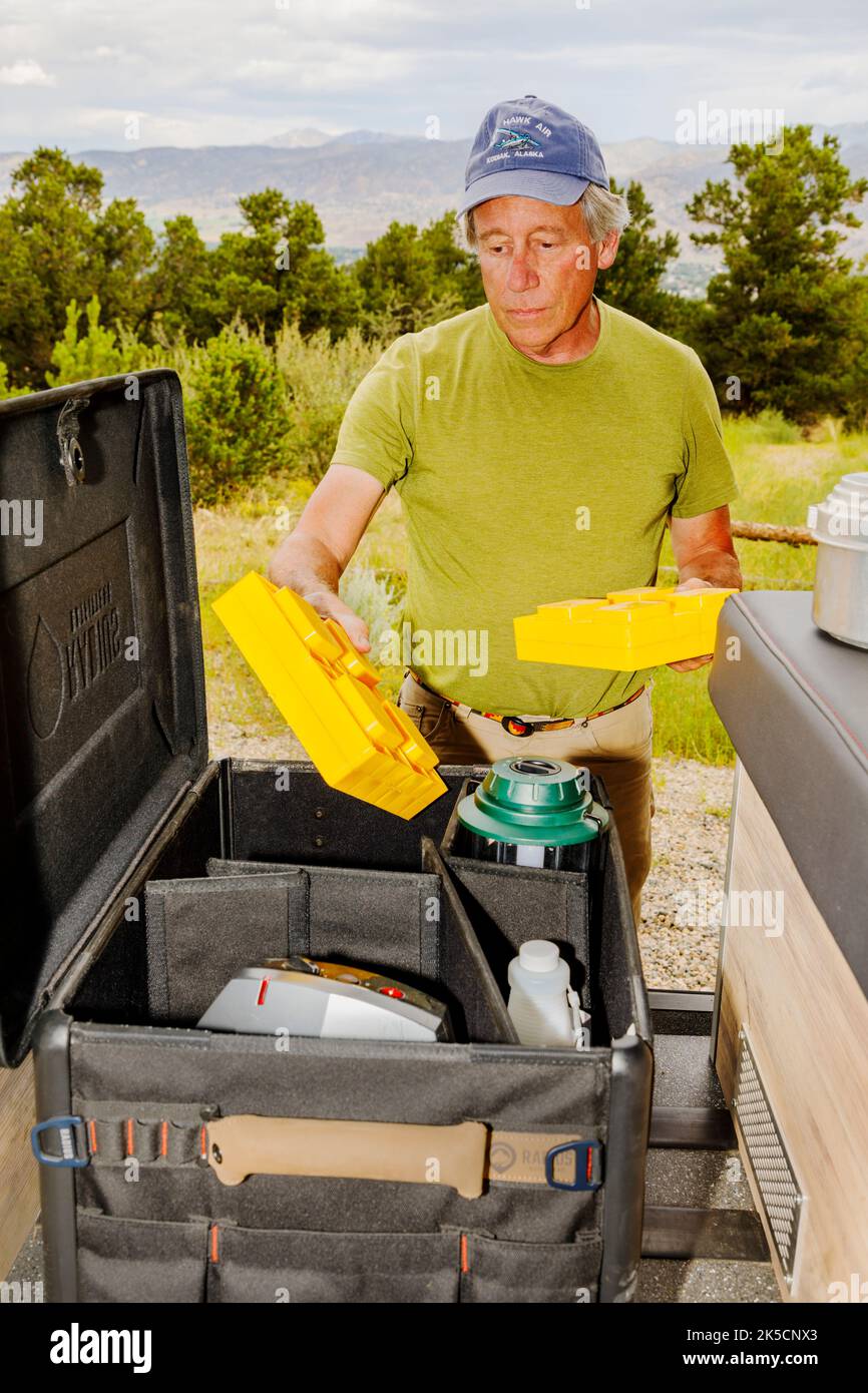 Man storing camping gear in Radius Outfitters Gear Box 500 Stock Photo