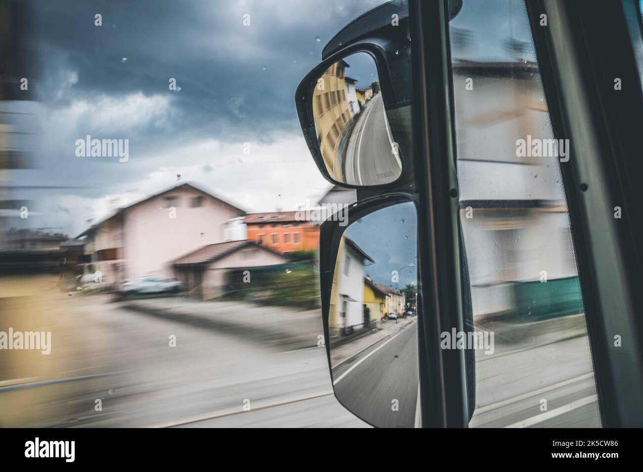 View of the road from the cab of a moving truck through the glass and rear view mirror Stock Photo