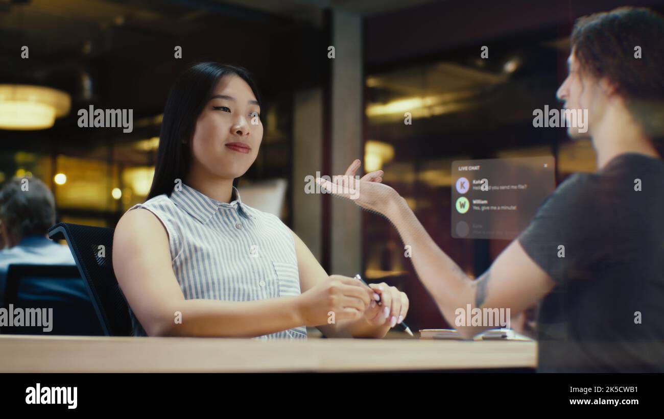 Young asian woman receives a call via an abstract futuristic screen hologram and starts talking to her friend. Futuristic communication scifi concept. 3D rendering picture. VFX. Stock Photo