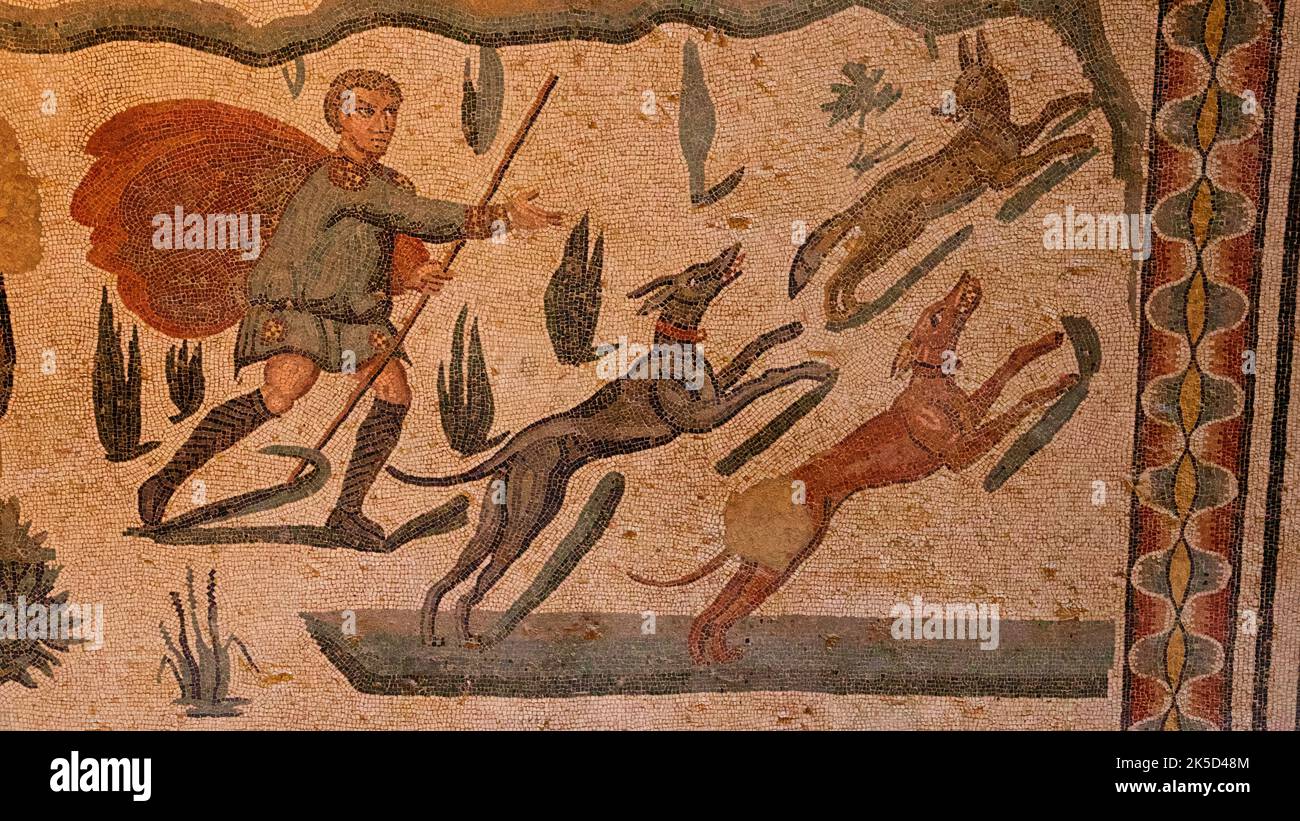 Italy, Sicily, Piazza Armerina, Villa Romana del Casale, Roman floor mosaics, hunting scene, hunter with spear and three dogs Stock Photo
