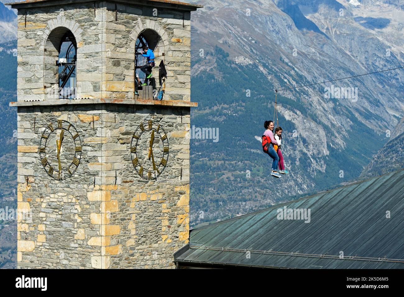 Mother and daughter glide down a rope slide from the church tower to the ground, Chinderwältfäscht, Kinderweltfest, Heidadorf Visperterminen, Valais, Switzerland Stock Photo
