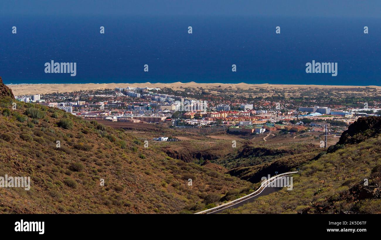 Spain, Canary Islands, Gran Canaria, south coast, Maspalomas, dune area, view from the entrance of Barranco de Fatah back and down to Maspalomas, dune strip, blue sea, road in the middle ground Stock Photo