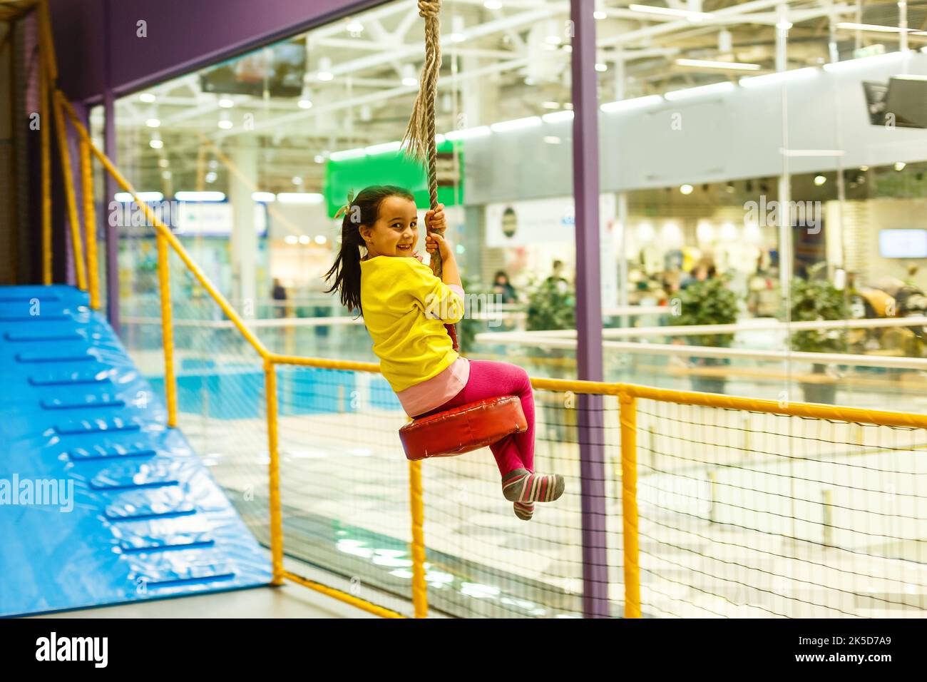 Adorable Little girl laughing happily, riding upside down on a bungee ...