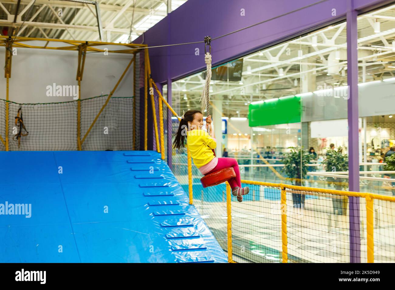 Adorable Little girl laughing happily, riding upside down on a bungee ...