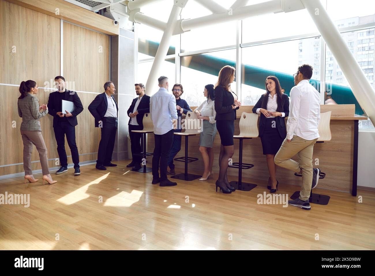 Group of people standing and talking in a modern office after a business event or a work meeting Stock Photo