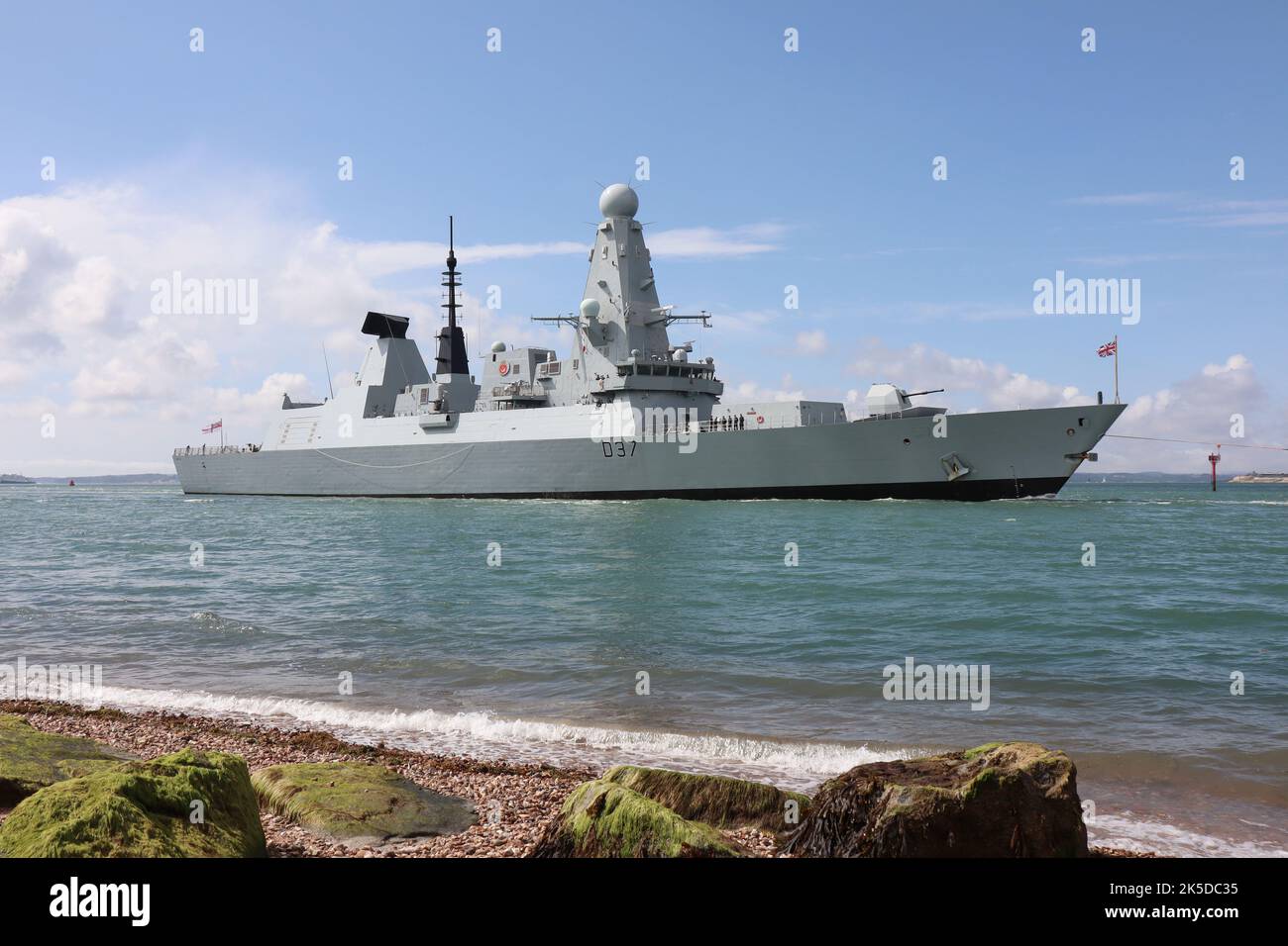 The Royal Navy Type 45 destroyer HMS DUNCAN passes close to the shoreline as it enters harbour and heads towards the Naval Base Stock Photo