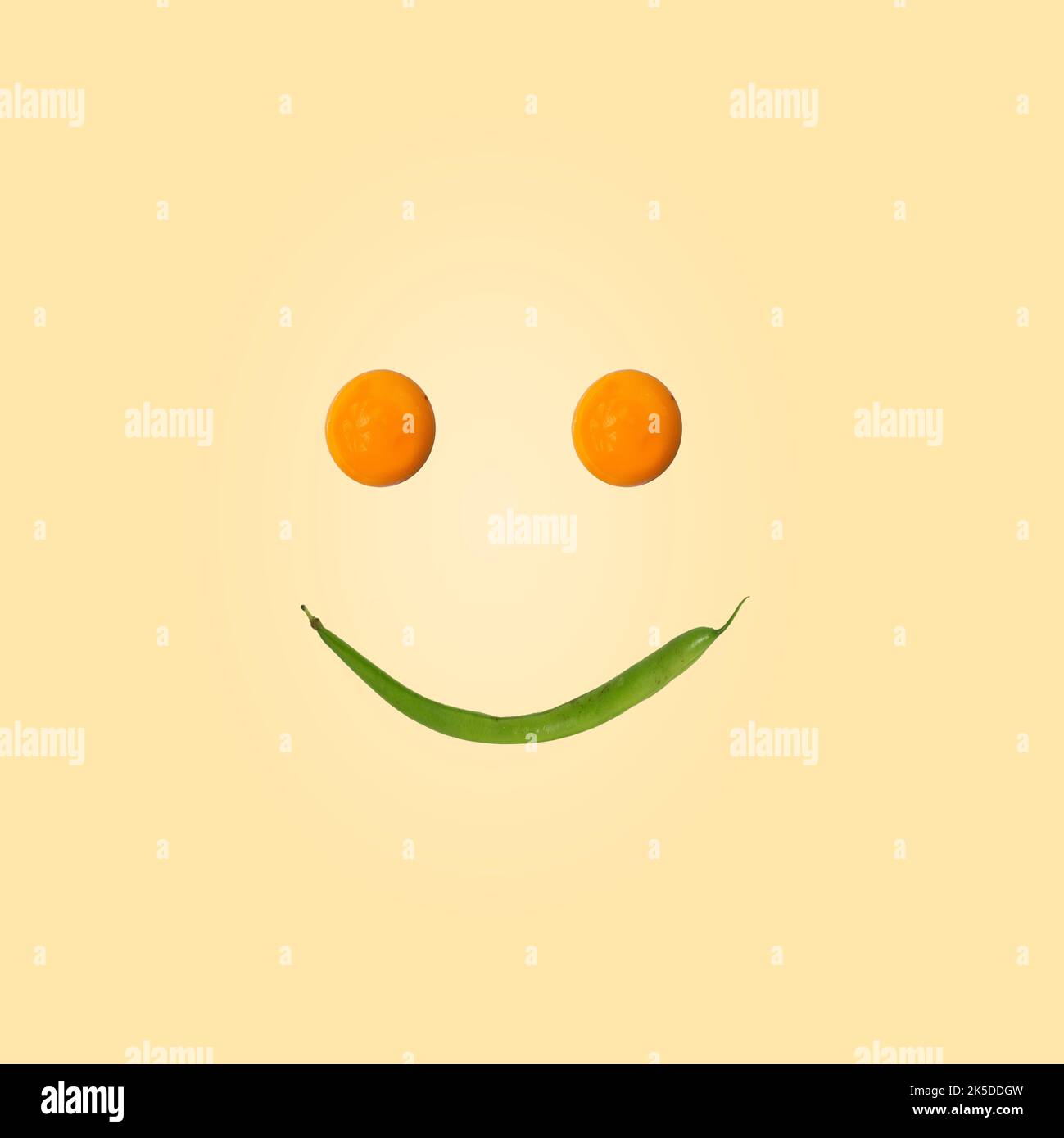 Eating is a pleasure. Smiling face made of green beans and yolks. Graphics on a light beige background. Modern food concept. Idea for an advertisement Stock Photo