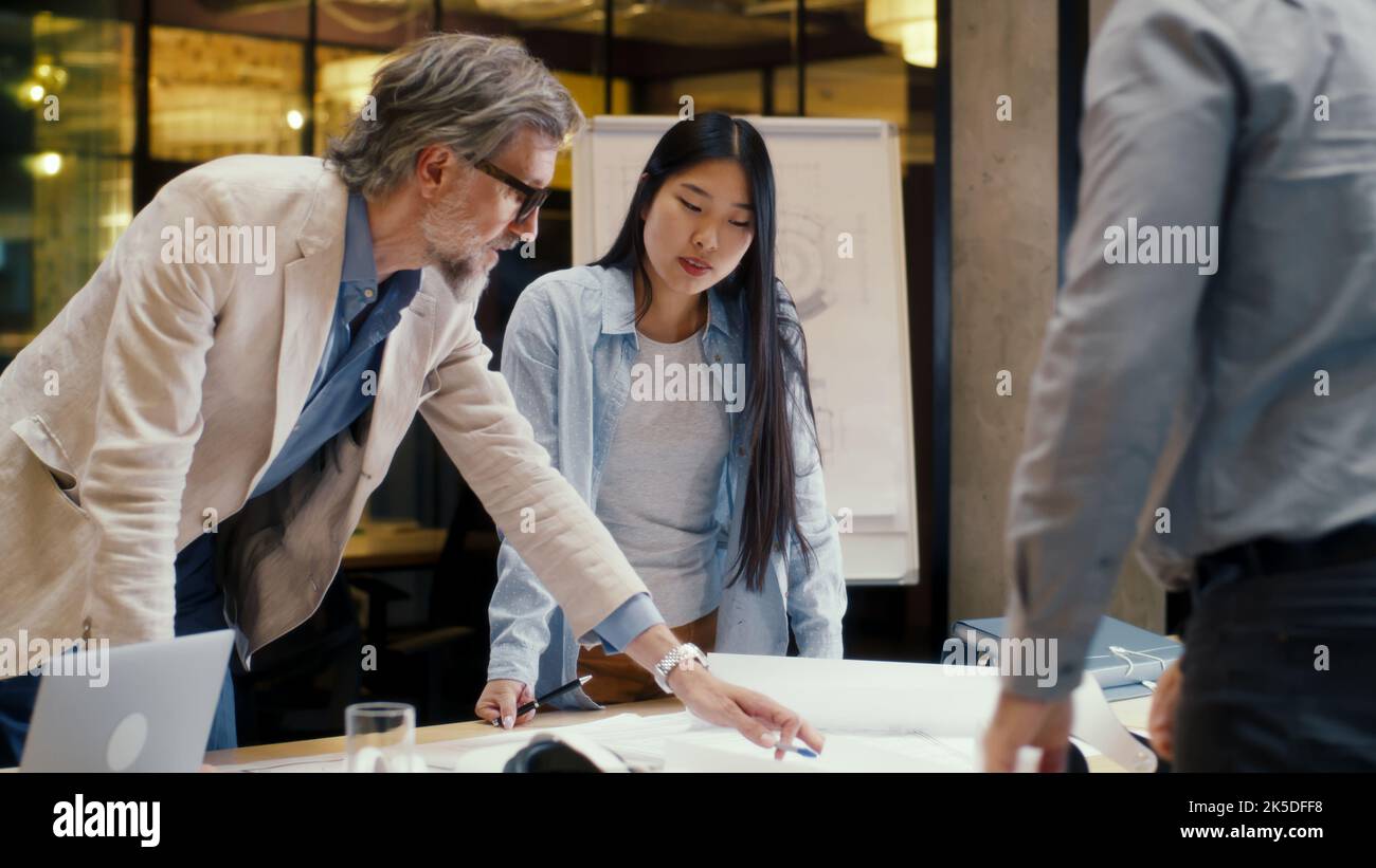 Strategy Engineers Multi-ethnic team of engineers looking through papers and blueprints ...