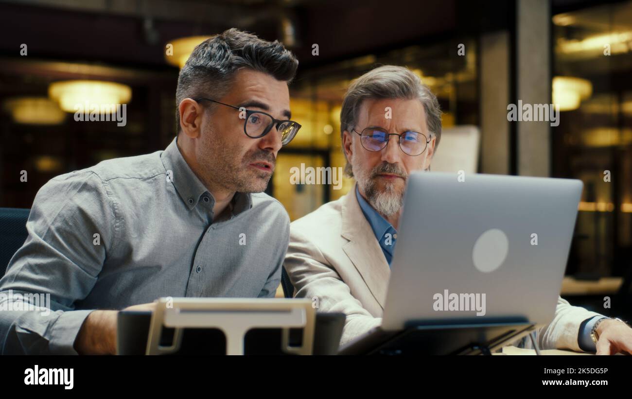 Men talking about business strategy and using laptop and digital tablet computer while sitting in modern office . E-commerce company. Bussinessmen working on startup project Stock Photo