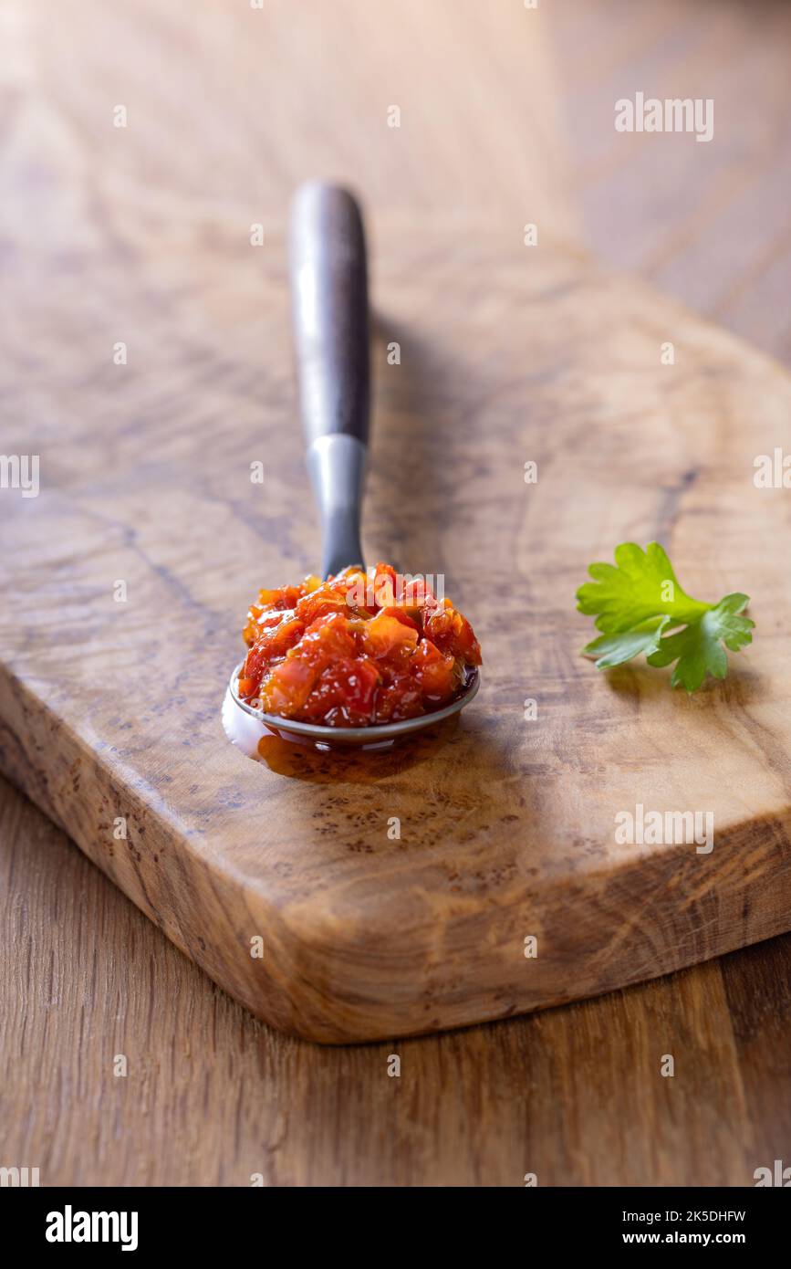 Hot paste made from chilli peppers and bell peppers with oil in a teaspoon - close up view Stock Photo