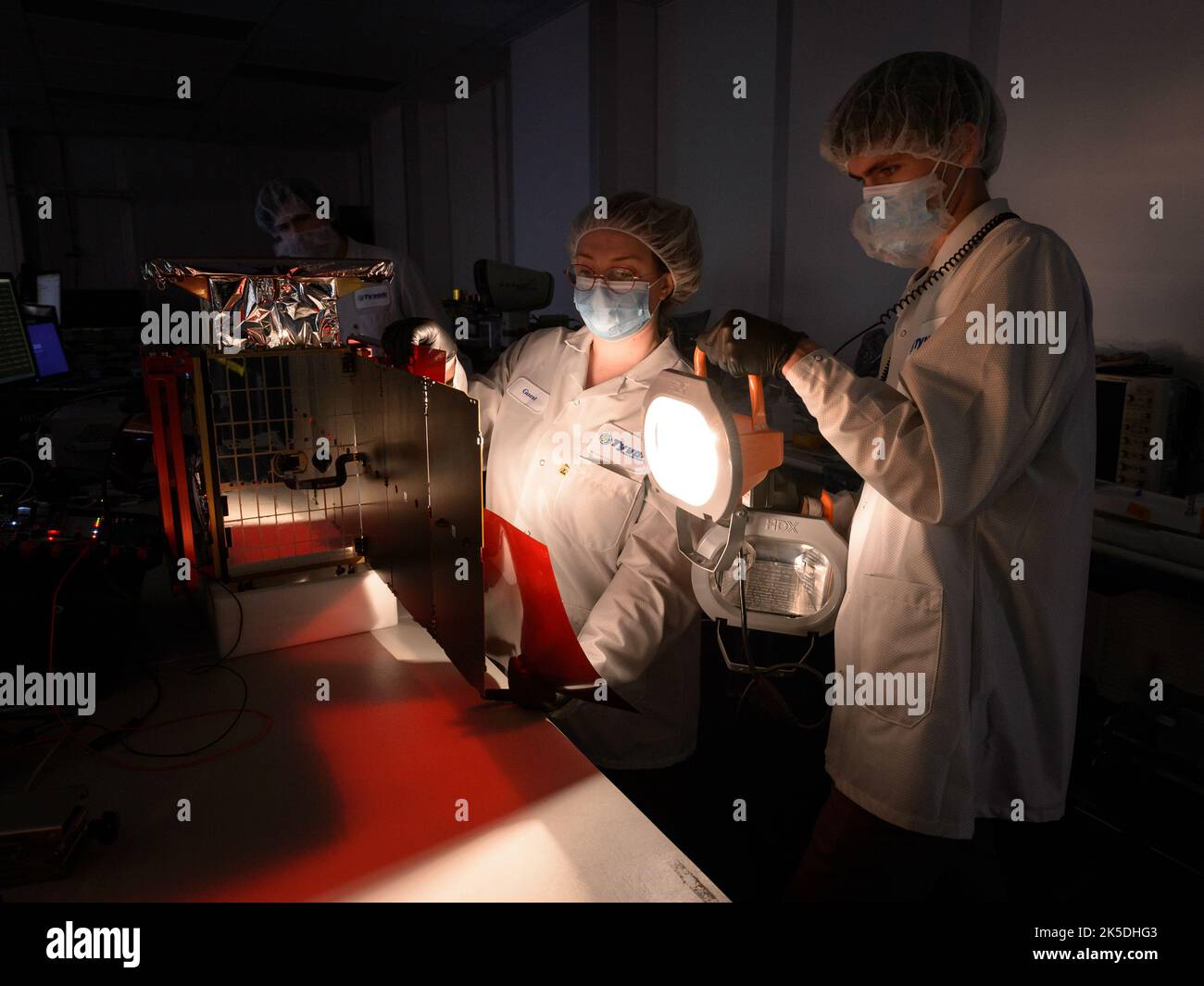 Rebecca Rogers, systems engineer, center, Lachlan Moore, systems integration engineer, right, and Dylan Schmidt, CAPSTONE assembly integration and test lead, background, perform a solar panel string voltage test of the CAPSTONE spacecraft at Tyvak Nano-Satellite Systems, Inc., in Irvine, California. Stock Photo