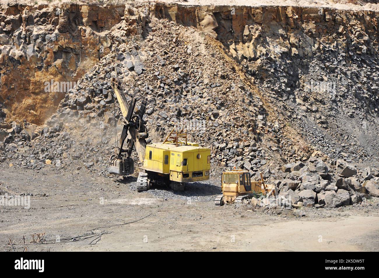 Stone mining in basalt quarry in process with massive rock on the
