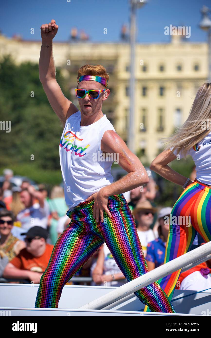 Brighton & Hove Pride Festival, Brighton & Hove, East Sussex, England. Man dancing on a float in multicoloured trousers and a 'Ford' Tshirt. Stock Photo