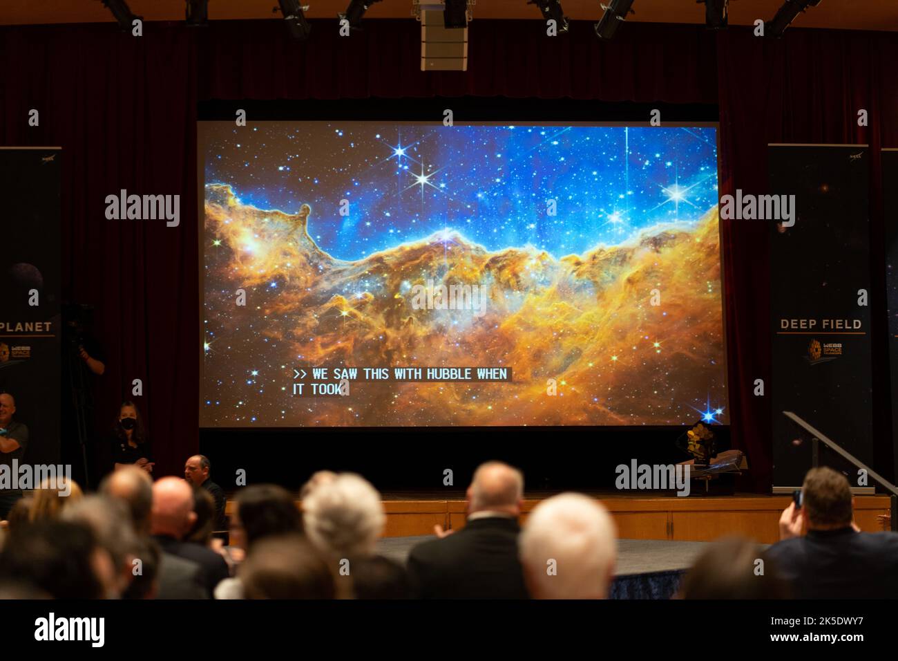 The image captured by NASA’s James Webb Space Telescope of the star-forming region called NGC 3324 in the Carina Nebula is seen on a screen as members of the media and guests watch the broadcast releasing the first full-color images from NASA’s James Webb Space Telescope, Tuesday, July 12, 2022, at NASA’s Goddard Space Flight Center in Greenbelt, Md.  The first full-color images and spectroscopic data from the James Webb Space Telescope, a partnership with ESA (European Space Agency) and the Canadian Space Agency (CSA), are a demonstration of the power of Webb as the telescope begins its scien Stock Photo