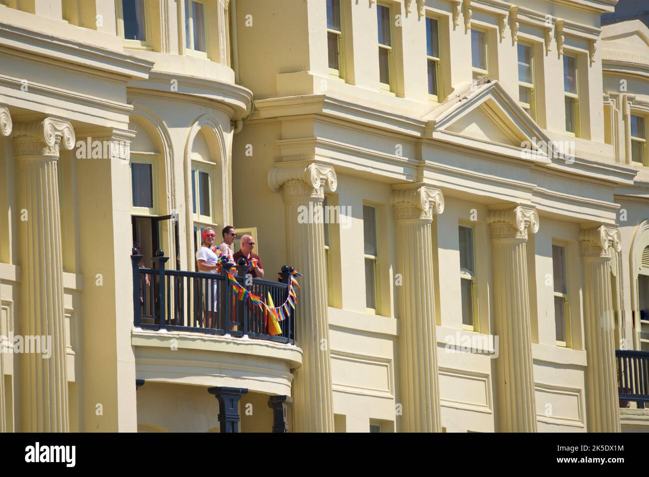 Brighton & Hove Pride Festival, Brighton & Hove, East Sussex, England. Locals looking on from the Regency architecture of Brunswick Terrace, Hove. Stock Photo