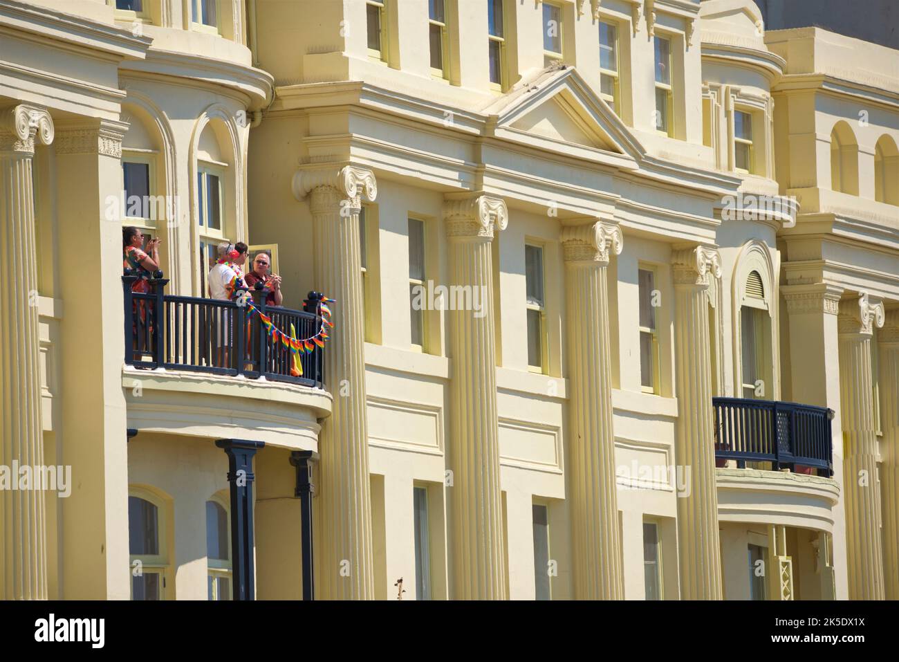 Brighton & Hove Pride Festival, Brighton & Hove, East Sussex, England. Locals looking on from the Regency architecture of Brunswick Terrace, Hove. Stock Photo