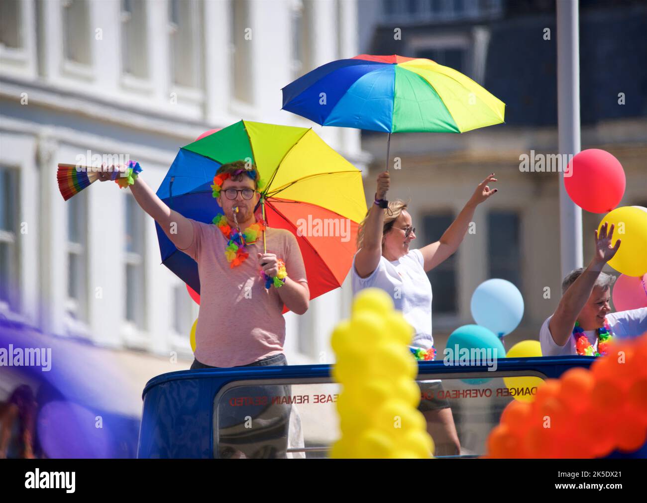 Brighton & Hove Pride Festival, Brighton & Hove, East Sussex, England. Participants with rainbow coloured parasols on an open deck bus. Stock Photo