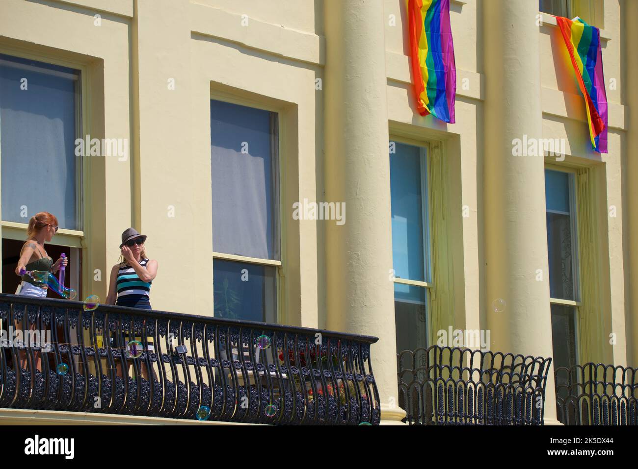 Brighton & Hove Pride Festival, Brighton & Hove, East Sussex, England. Locals looking on from the Regency architecture of Brunswick Terrace, Hove. Stock Photo