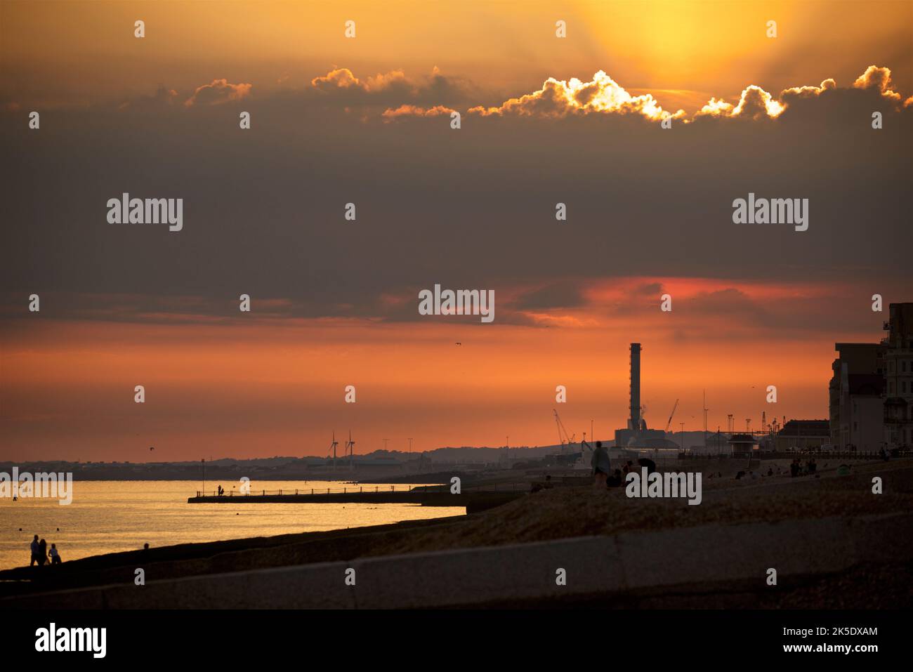 Shoreham Power Station in the distance taken from beach in Hove. Sunset and moody clouds in the sky. Stock Photo