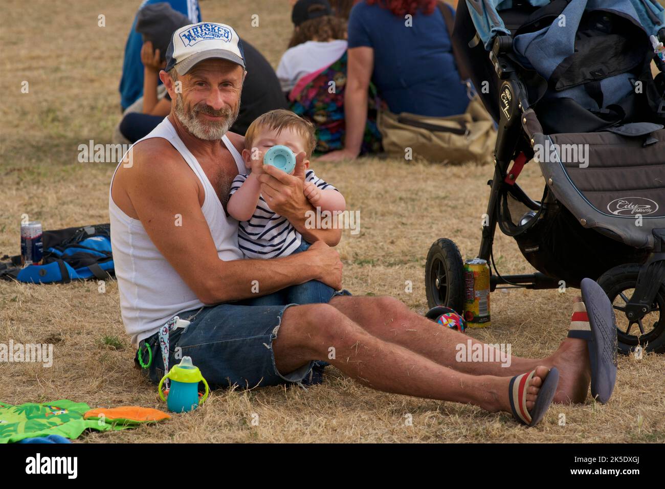 Father and baby soon enjoying the vibes at Brunswick Square Gardens for the annual Brunswick Festival, August. Hove, Brighton & Hove, East Sussex, England Stock Photo