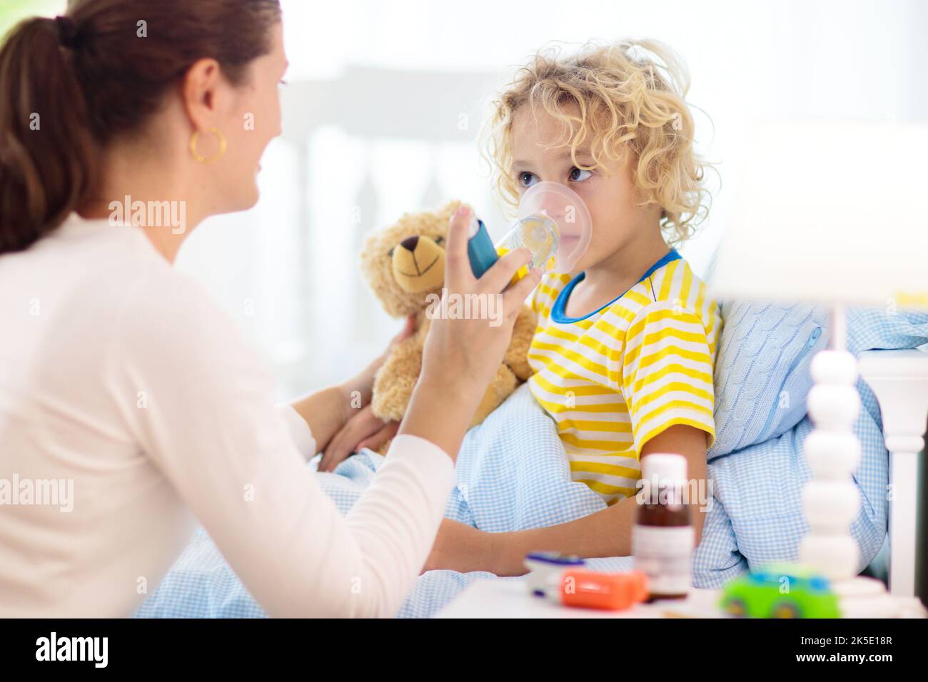 Sick little boy with asthma medicine. Mother with ill child lying in
