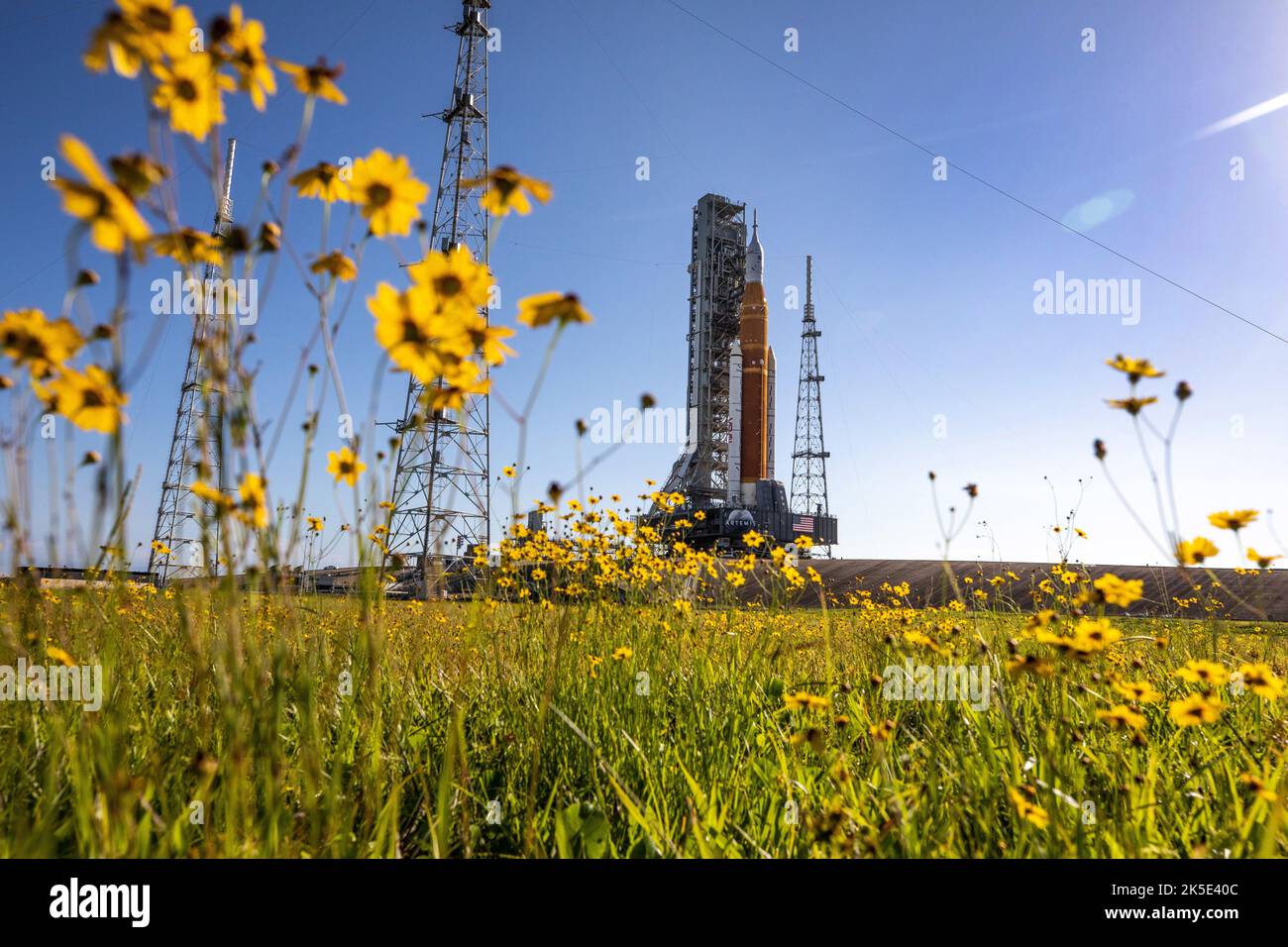 With wildflowers surrounding the view, NASA's Space Launch System (SLS) Moon rocket carried atop the Crawler-Transporter 2 arrives at LaunchPad 39B at the agency's Kennedy Space Center, Florida on June 6, 2022. The first in an increasingly complex series of missions, Artemis I will test the SLS rocket and Orion spacecraft as an integrated system prior to crewed flights to the Moon. Through Artemis, NASA will land the first woman and first person of colour on the Moon, paving the way for a long-term lunar presence and using the Moon as a steppingstone to Mars  Credit: NASA/ Smegelsky Stock Photo