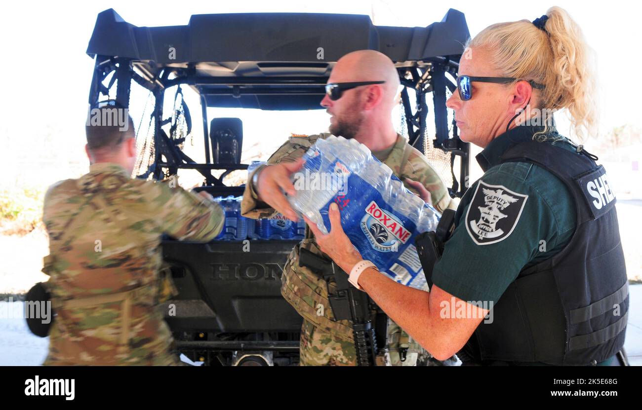 Florida Army National Guard Spc. Caleb Cartwright assigned to Charlie Troop, 1st Squadron, 153rd Calvary Regiment unloads water from a Lee County Sheriff deputy’s vehicle during emergency response efforts from Hurricane Ian in Sanibel Island Florida 3, Oct. 2022. Supplies such as food and water were cut off from the island due to Hurricane Ian’s destruction that restricted residents from entering or exiting by land. (Florida Army National Guard photo credit by Staff Sgt. Cassandra Vieira) Stock Photo