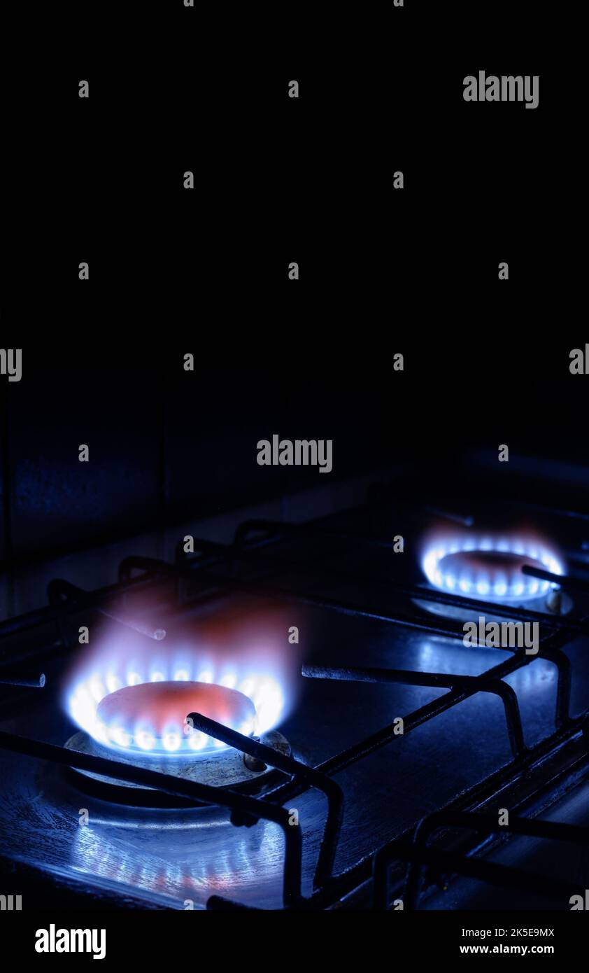Propane gas burns on dark background with black copy space, vertical view of gas stove and blue