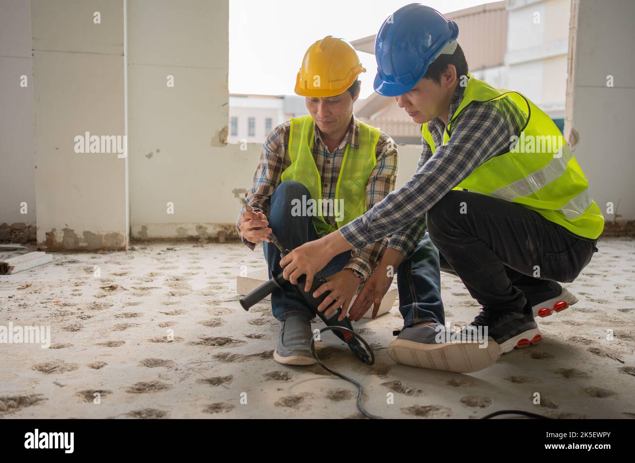 Engineer teaching worker for use electric jackhammer for perforator equipment making holes the floor to be strong at construction site, Concept of wor Stock Photo