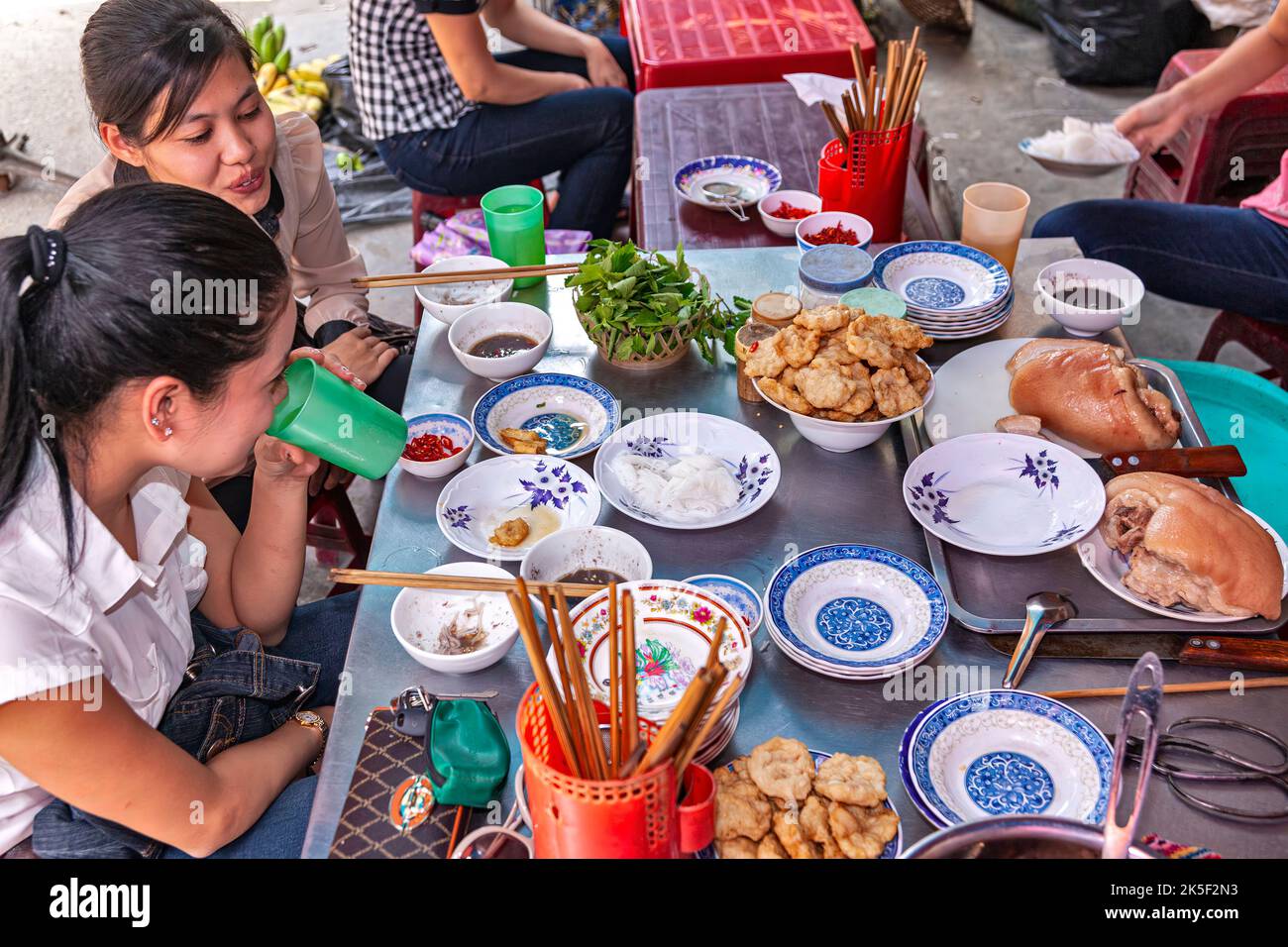 Vietnamese girls eating at open air street restaurant, Hai Phong, Vietnam Stock Photo