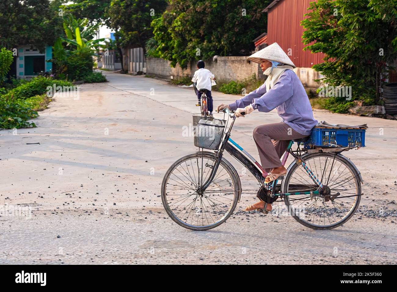 Vietnamese lady wearing bamboo hat riding bicycle, Hai Phong, Vietnam Stock Photo