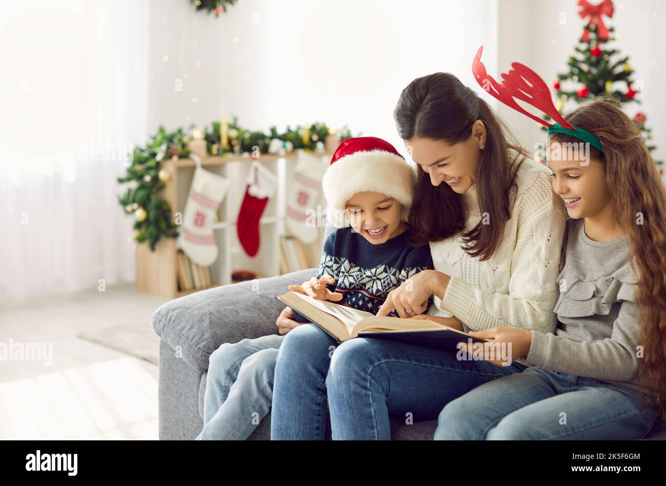 Happy mother and children read book on winter holidays Stock Photo