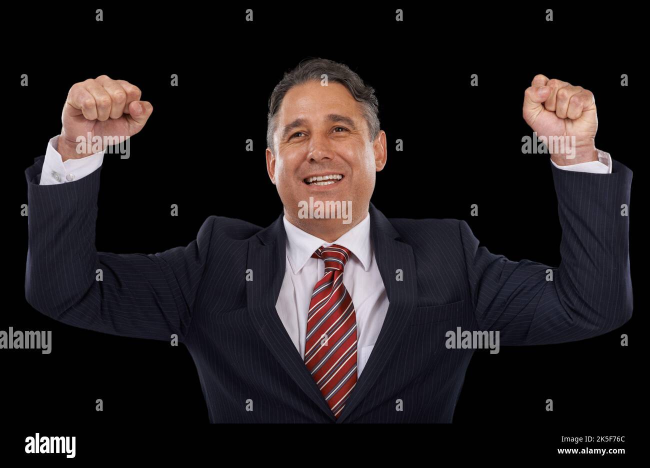 Celebrating victory. A man in a suit with his arms raised in celebration - black background. Stock Photo