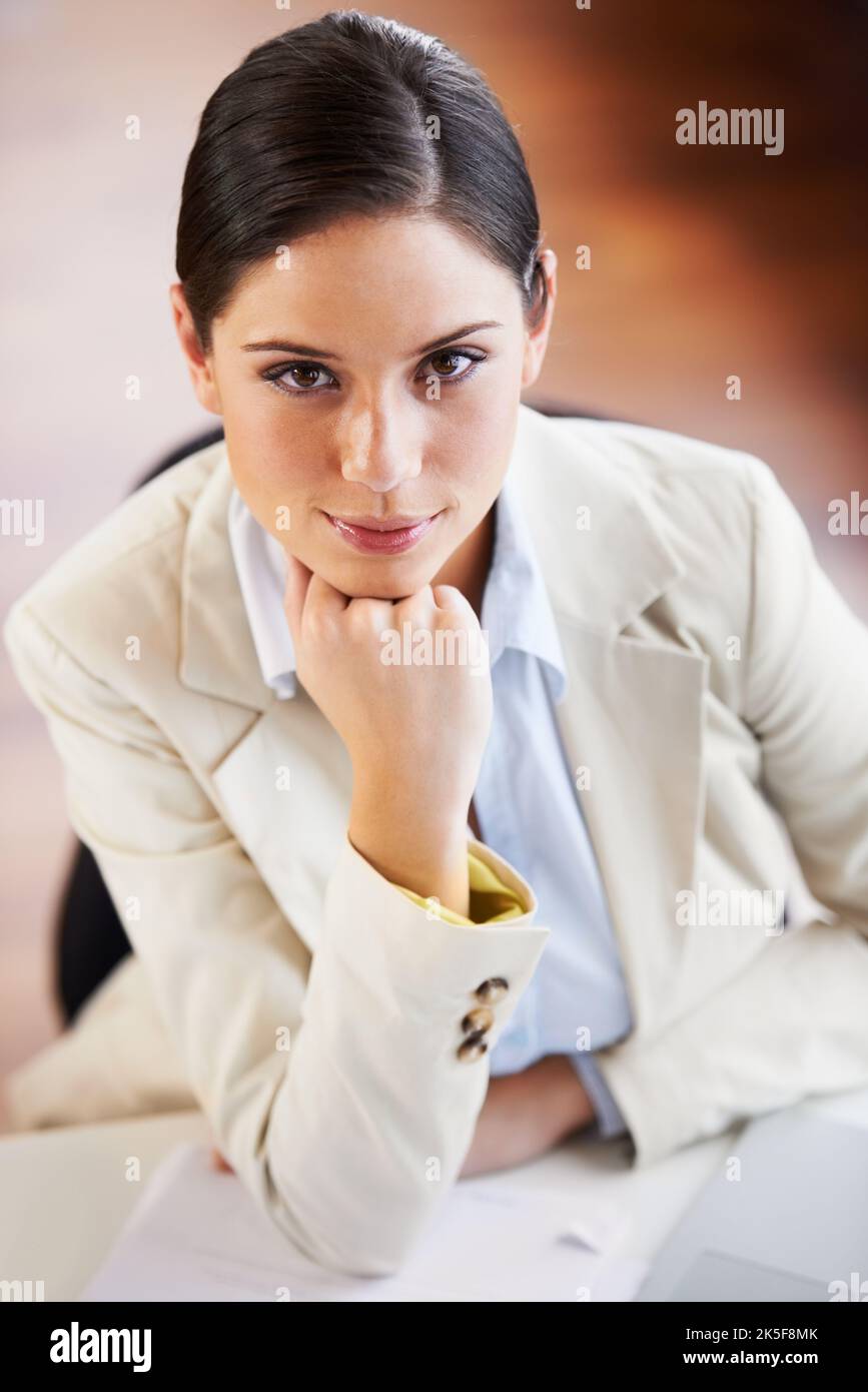 She wont be looking up the corporate ladder for long. Portrait of a young businesswoman sitting at a desk in an office. Stock Photo