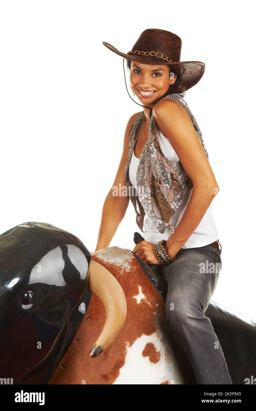 Ready for a ride. Studio shot of a beautiful young woman riding a mechanical bull against a white background. Stock Photo