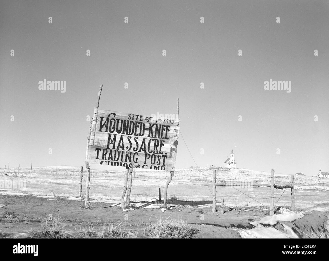 John Vachon - Wounded Knee Massacre Trading Post Signage and Sacred Heart Catholic Church at Wounded Knee, South Dakota - c1940 Stock Photo