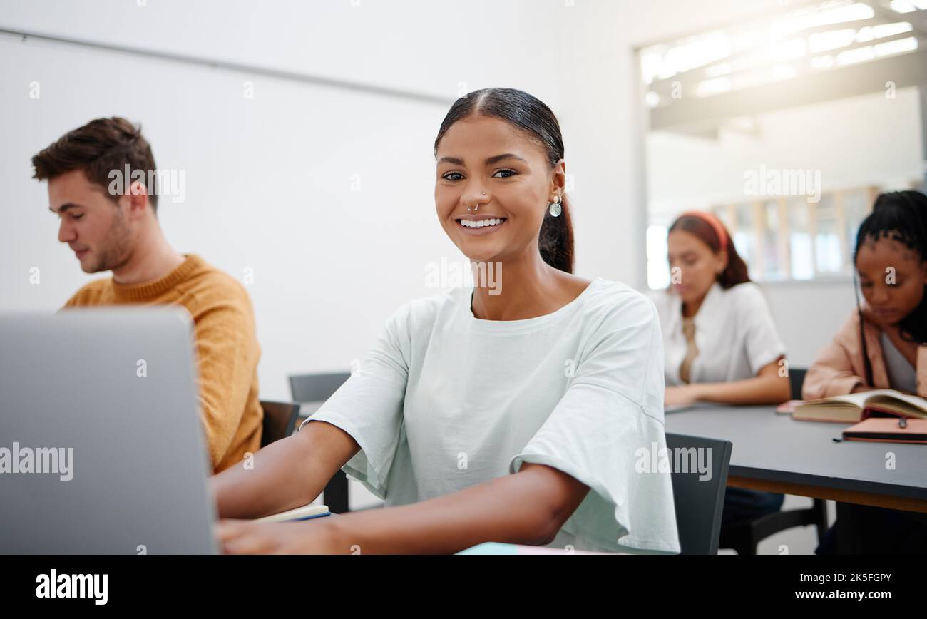 College student portrait, lecture classroom and laptop typing notes, learning and education for school, campus and university. Happy woman studying Stock Photo