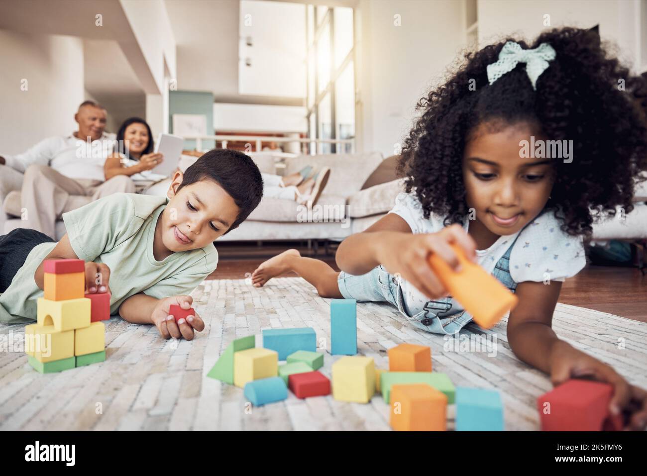 Kids, building blocks and creative learning in family home, living room floor and ground for growth, development and fun. Focus children, educational Stock Photo