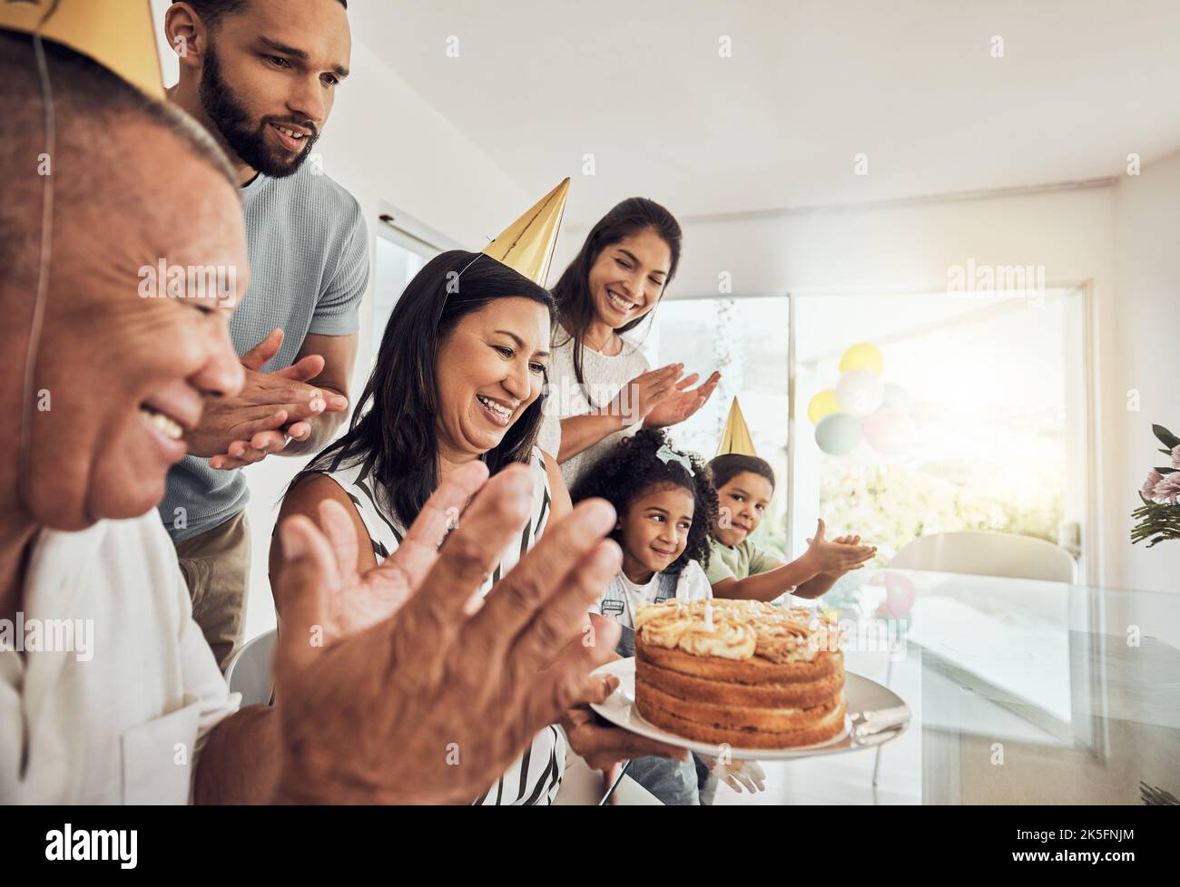 Family, happy and birthday with grandmother and celebration in dining room for party, love and cake. Smile, wow and event together with big family for Stock Photo