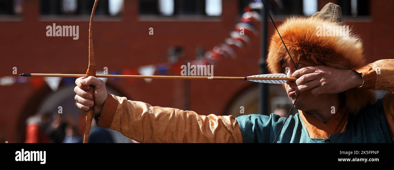 Medieval archery tournament. Man shoots an arrow in the medieval castle