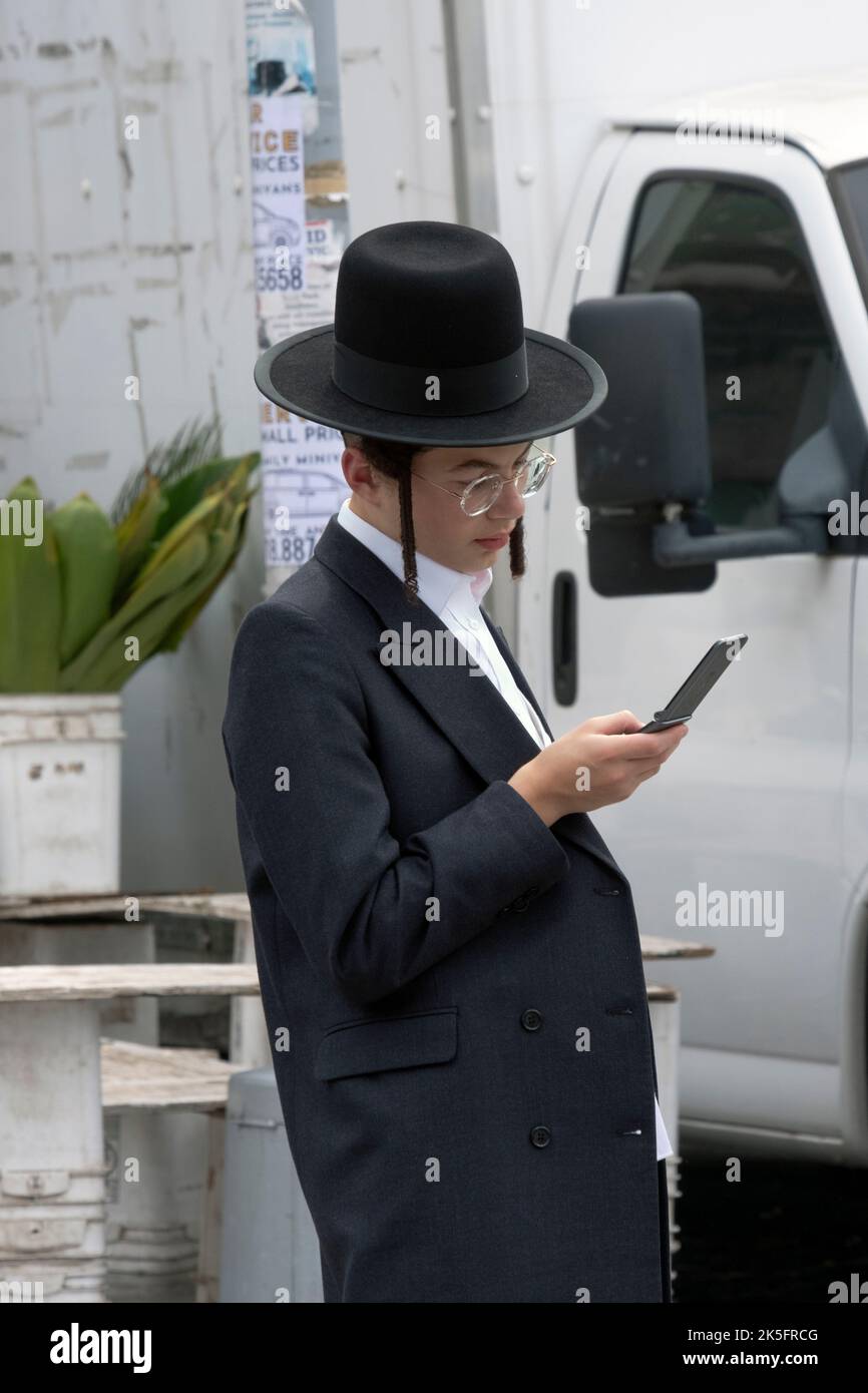 A Hasidic Jewish young man checks his flip phone on Bedford Avenue in Williamsburg, Brooklyn, New York City. Stock Photo
