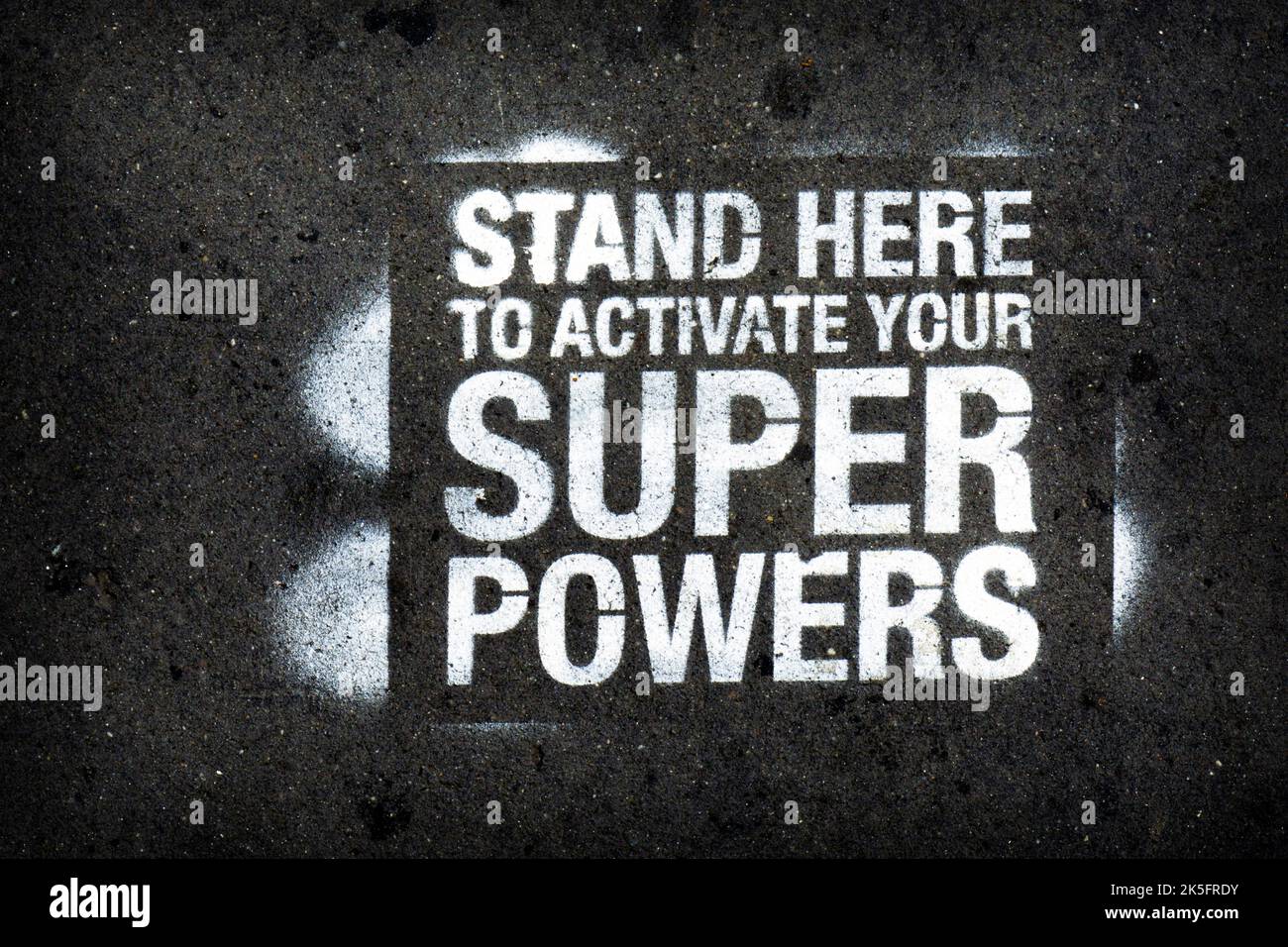 A fun message on the ground saying 'Stand here to Activate your Super Powers.' In Washington Square Park. Stock Photo