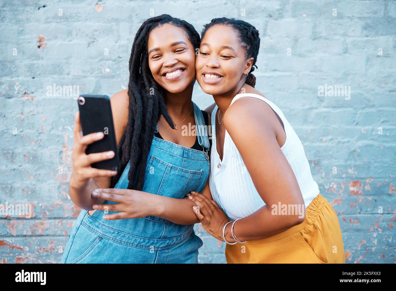 Black women, friends and selfie while smiling and happy outside against city or urban wall and posing for friendship social media picture outside Stock Photo