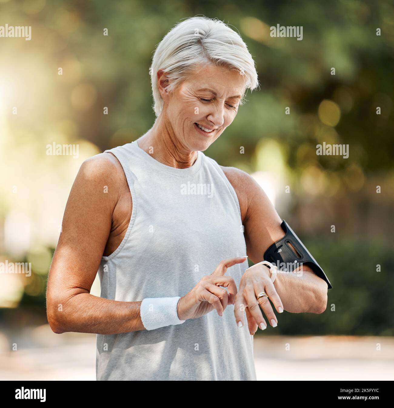 Senior woman, fitness and watch of running time in health and wellness for cardio exercise in nature. Active elderly female runner checking smartwatch Stock Photo