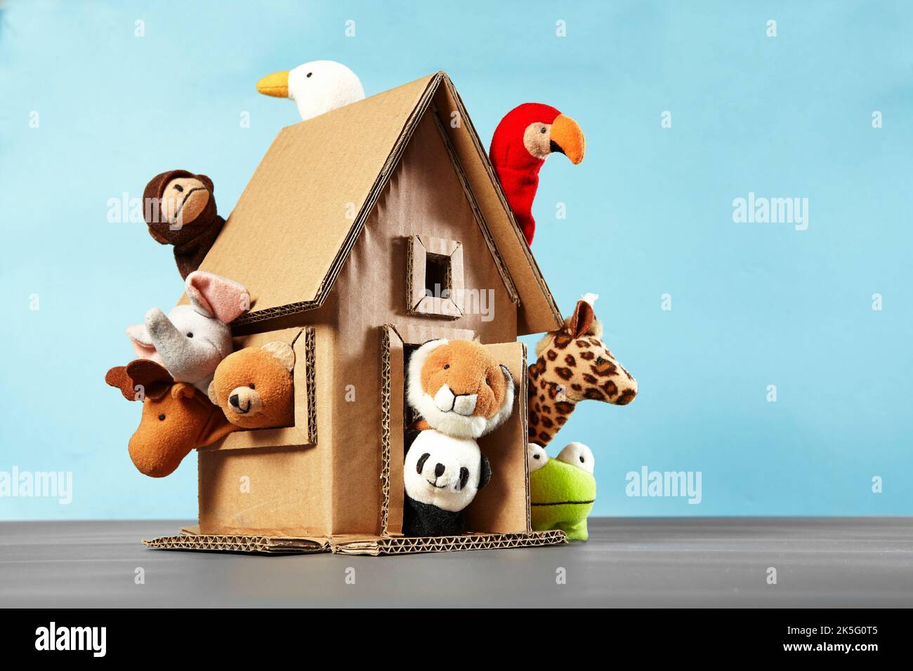 Ten animal finger puppets coming out of a cardboard craft house on a