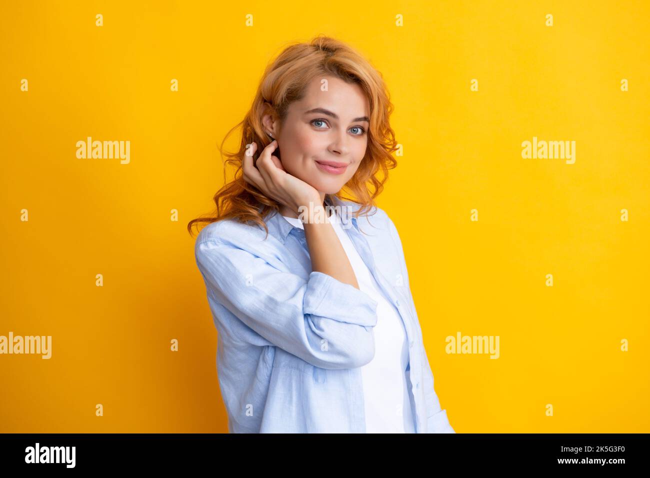 Redhead woman portrait. Female model face. Beautiful redhead woman smiles cheerfully isolated on yellow background. Stock Photo