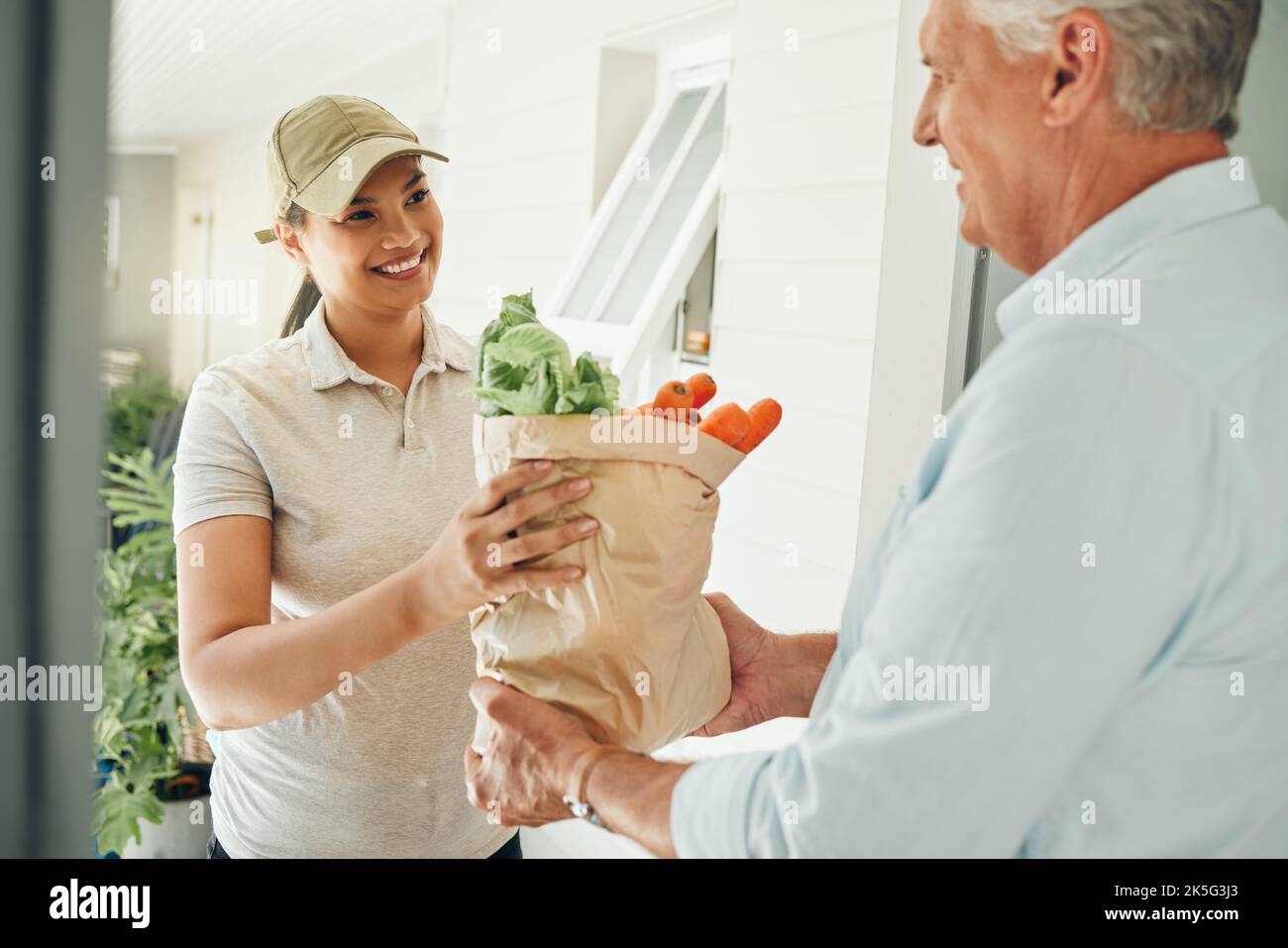 Home delivery service, fresh vegetables and customer paper bag logistics of healthy groceries at front door house. Happy woman courier giving organic Stock Photo