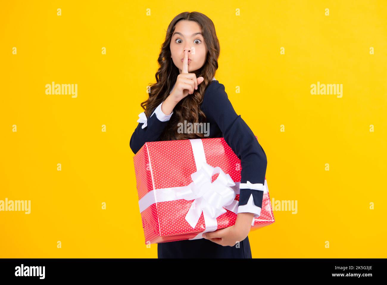 Funny face with shhh secret. Teenager child with gift box. Present for holidays. Happy birthday, Valentines day, New Year or Christmas. Kid hold Stock Photo